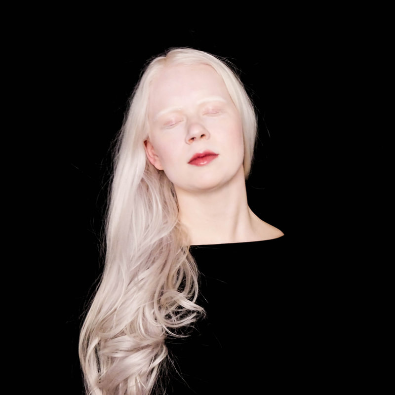 Tamara against a black background with her eyes closed during a performance